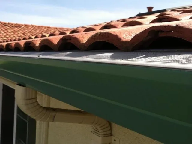 GutterDome gutter guard fitted to a Spanish tile roof above a green gutter