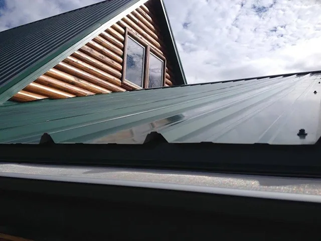 GutterDome GD45 Adjustable gutter guard installed on a dark green corrugated metal roof, straight run.